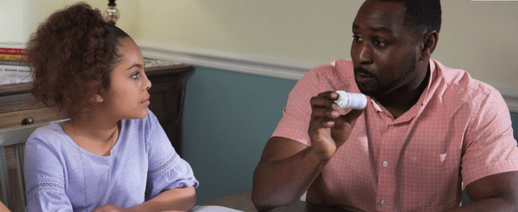 Dad holding pill bottle talks with daughter